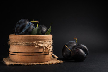 Garden plums in bowl on stone table. View with copy space