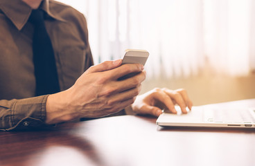 businessman using cell phone with laptop working in office vintage tone.