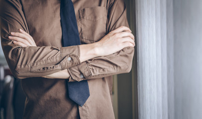 Businessman standing thinking and cross one's arm near window.