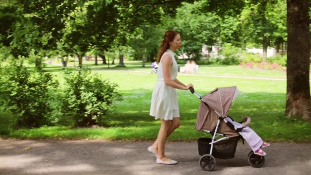 happy mother with baby in stroller walking at park