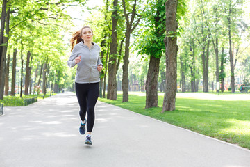 Young woman running in green park, copy space