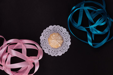 Wheat cookie on white napkin with rose and blue ribbon on black background