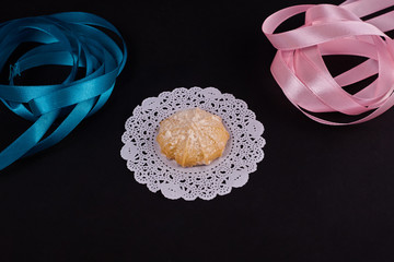 Wheat cookie on white napkin with rose and blue ribbon on black background