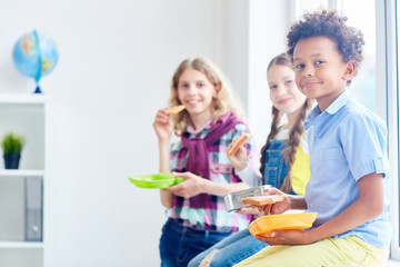 Cute school friends having lunch at break between lessons