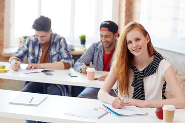 Young student carrying out task during final exam at college