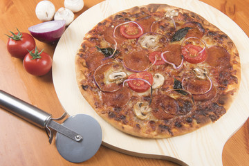 Cooked pepperoni pizza with mushrooms and onions and a pizza slicer