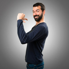 Handsome man with beard proud of himself on grey background