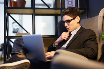 Young specialist with laptop searching for job in the net