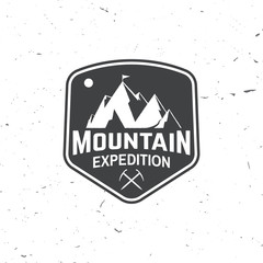 Vintage typography design with ice ax and mountain silhouette.