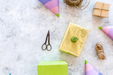 Preparing to celebration. Colored gift boxes and party hats on grey stone background top view copyspace