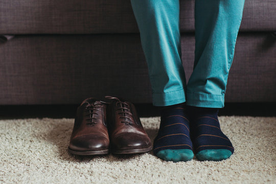 The man seats near shoes on the sofa