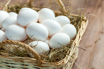 Chicken eggs in basket on wooden background