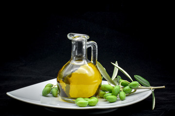 some olives and a jar full of oil on a black background