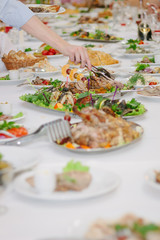 Catering table - hand with tongs taking a food.