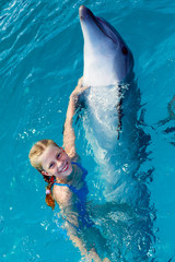 Naklejka premium Happy child and dolphins in blue water. Dolphin Assisted Therapy