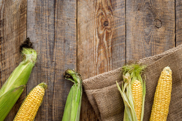 Vegetarian food. Corn cobs on rustic wooden background top view copyspace