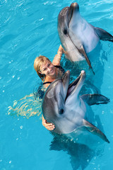 Fototapeta premium Coach swims in the water with dolphins. Dolphin Assisted Therapy.