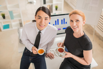 High angle view of multi-ethnic group of coworkers looking at camera with wide smiles while...