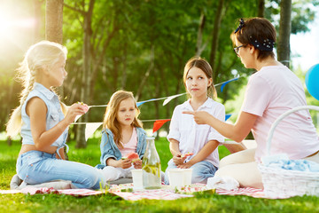 Kindergarten teacher shaming little girls during picnic or outdoor party in park