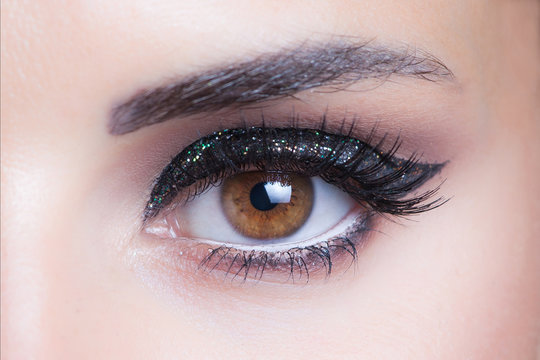 woman eye with glittering evening makeup closeup studio