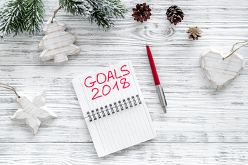Set a goal for new year 2018. Notebook near pen on grey wooden background top view