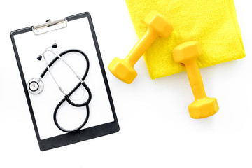 Sport and health. Fitness. Dumbbells and stethoscope on white background top view