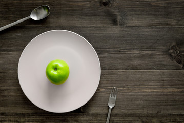 Slimming diet. Apple at plate on wooden background top view copyspace