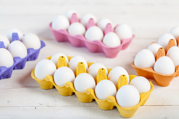 White eggs in colorful boxes on  rustic wooden table, modern concept