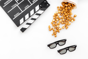 To go to the cinema. Clapperboard, glasses and popcorn on white background top view copyspace
