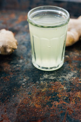 ginger juice in small glass jar with ginger root behind.
