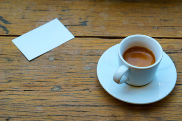 Obraz na płótnie Canvas close up. espresso coffee in white cup with white business card on the wooden table. business coffee concept. vintage tone