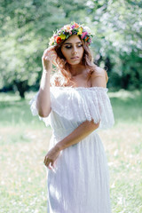 Fototapeta premium Bride in a wedding dress staying on the green forest.