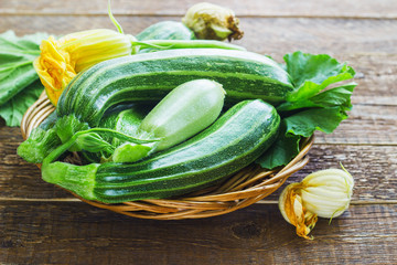 Fresh zucchini on wicker mat on dark wooden background