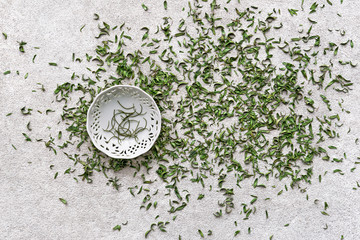 Small dish on green tea leafs background.