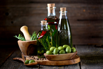 Organic olive oil with spices and herbs on an old wooden background. Healthy food.