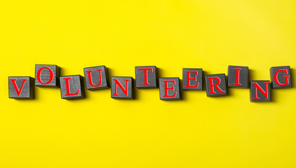 Volunteering concept. Wooden cubes on color background