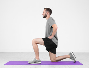 Obraz premium Young man performing lunges on yoga mat, fitness and healthy lifestyle, home workout exercise routine