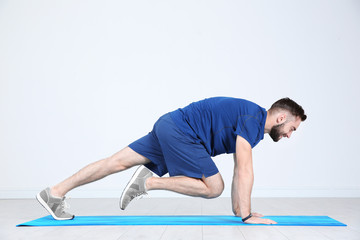 Fototapeta na wymiar Sporty young man training legs on mat in gym