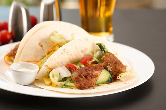 Delicious fish tacos served on white plate on table, close up