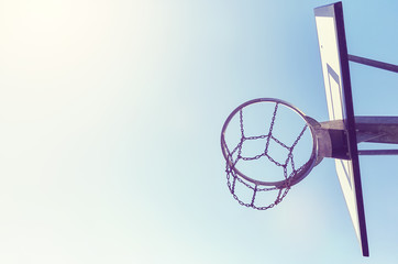 Basketball hoop with chain net at sunset, color toning applied, space for text. © MaciejBledowski