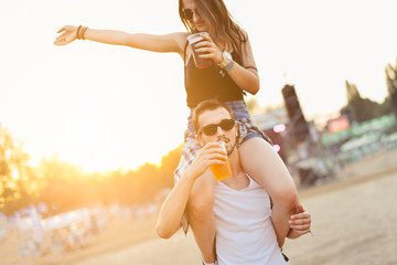 Young couple drinking beer and having fun at the music festival 
