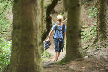 Young child boy walking during the hiking activities in forest. Outdoors leisure for child in summer