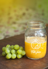 Homemade  fresh orange juice in a glass jar and grapes isolated on wooden background
