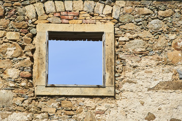 Blue sky visible through an old broken window in an abandoned building