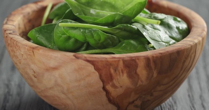 fresh spinach leaves in olive bowl on wood table