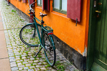 Fototapeta na wymiar Bicycle near the orange wall of old building in Copenhagen, Denmark. Copenhagen style, Denmark bicycle, european street