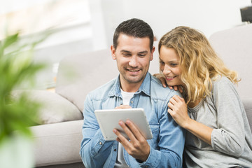 Relaxed young couple using a tablet in their living room