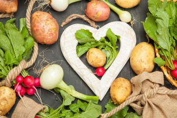 Radishes, potatoes and onions on a black background
