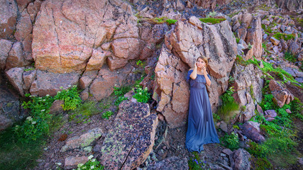 Girl in a long dress against the background of a rock