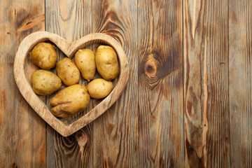 Potatoes in the heart on a wooden background